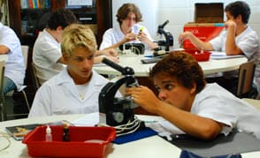 dois alunos olham em um microscópio durante aula de ciências