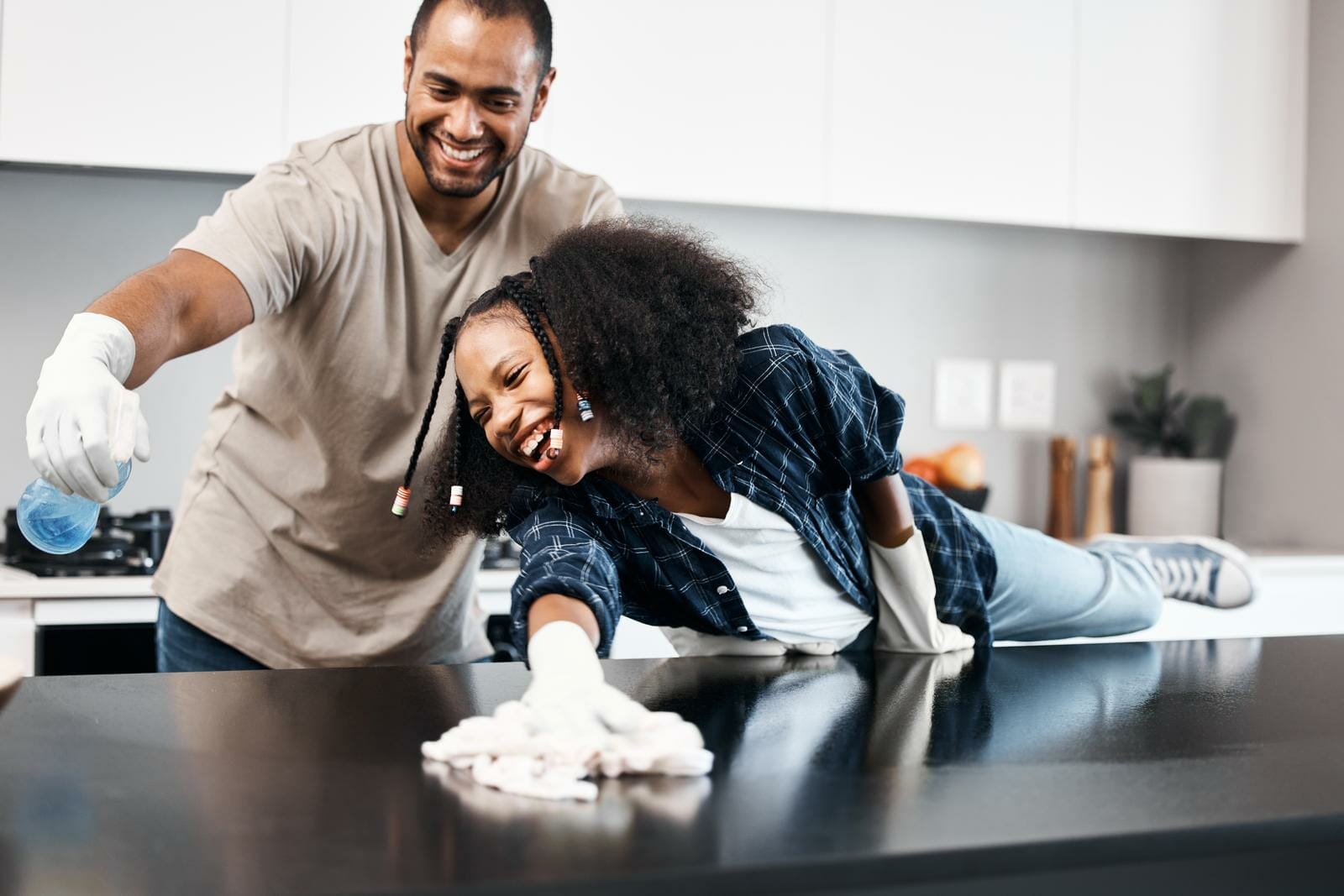 pai e filha sorrindo enquanto limpam o balcão da cozinha