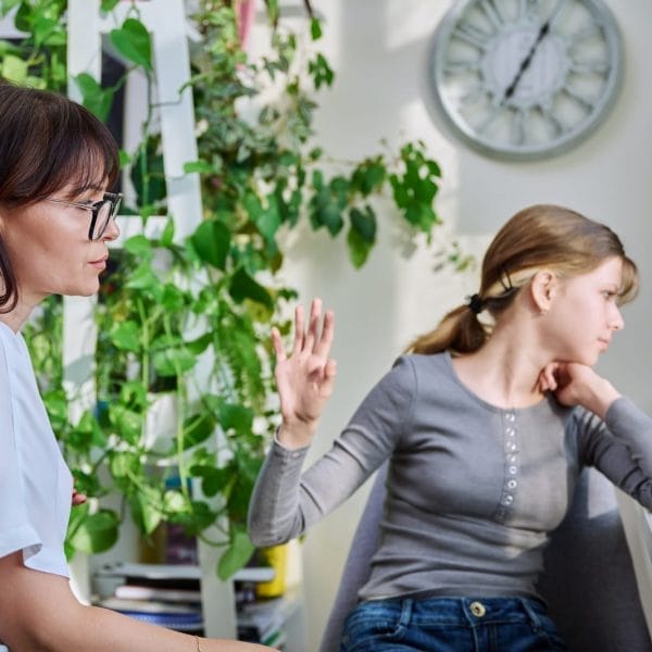 mãe e adolescente brigando, com a filha sentada e virando a cara. representa o conceito de pais em busca de fazer as pazes com sua filha