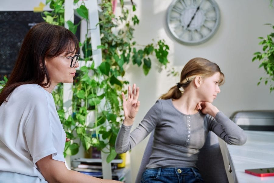 mãe e adolescente brigando, com a filha sentada e virando a cara. representa o conceito de pais em busca de fazer as pazes com sua filha