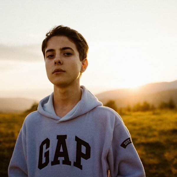 Adolescente de casaco brando em primeiro plano. Fundo de uma paisagem de campo desfocada