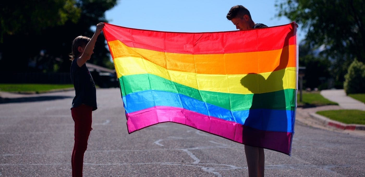 adolescentes segurando bandeira LGBTQIA+, representando o conceito de ideologia de gênero nas escolas