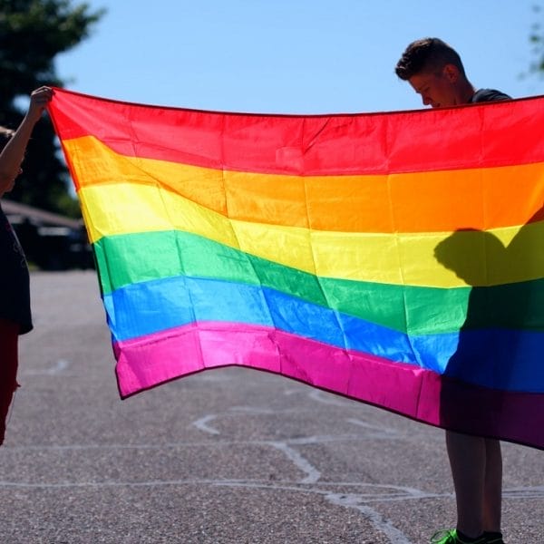 adolescentes segurando bandeira LGBTQIA+, representando o conceito de ideologia de gênero nas escolas