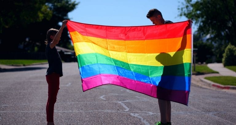 adolescentes segurando bandeira LGBTQIA+, representando o conceito de ideologia de gênero nas escolas