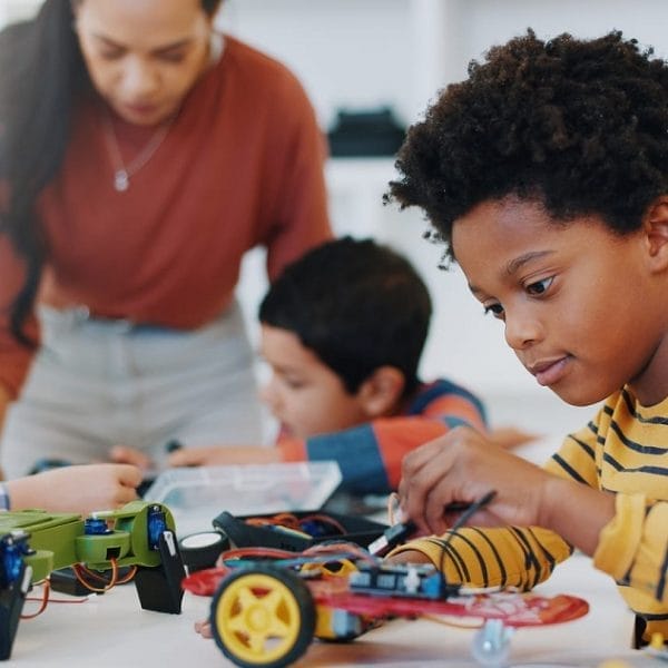 aluno sentado em uma mesa montando carro de controle remoto, em aula de robótica, que representa os métodos das escolas inovadoras