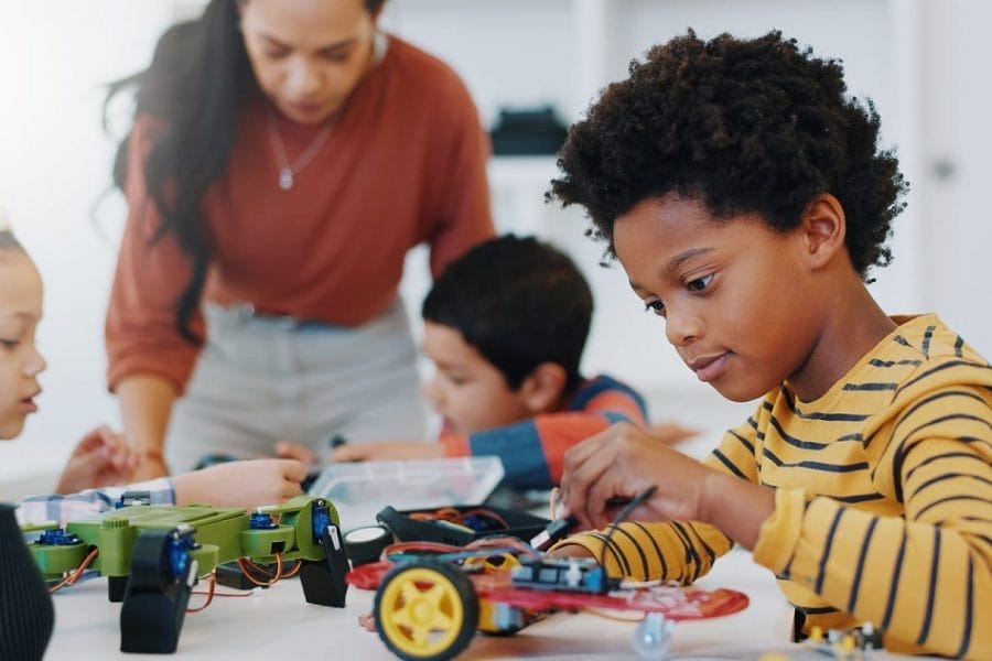 aluno sentado em uma mesa montando carro de controle remoto, em aula de robótica, que representa os métodos das escolas inovadoras