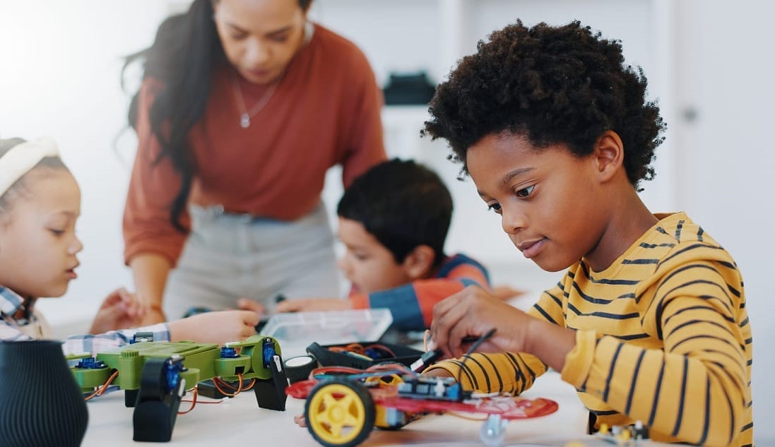 aluno sentado em uma mesa montando carro de controle remoto, em aula de robótica, que representa os métodos das escolas inovadoras