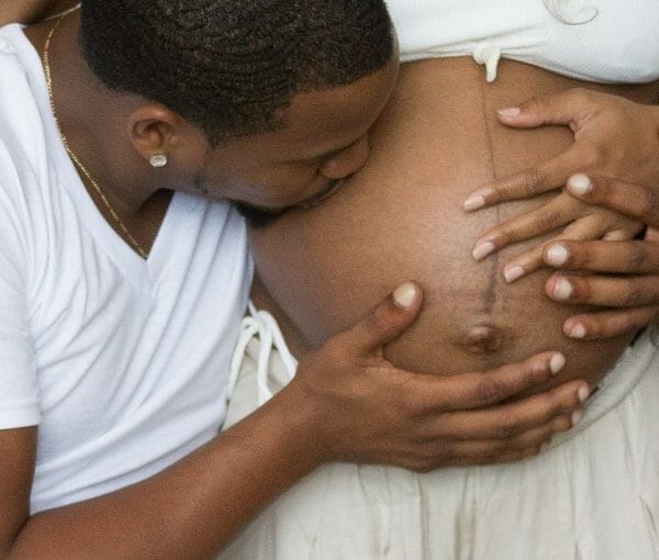 esposo beijando a barriga da gestante que está com a linha nigra