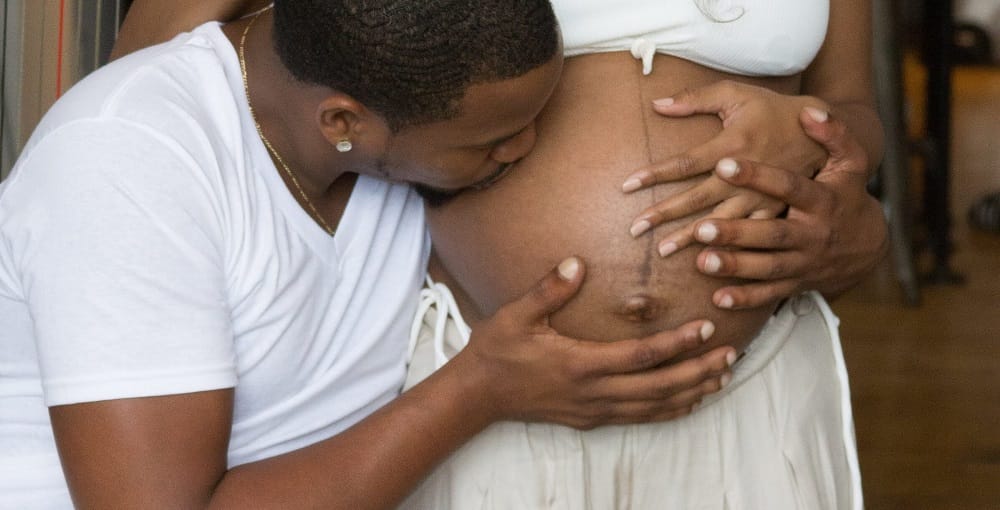 esposo beijando a barriga da gestante que está com a linha nigra
