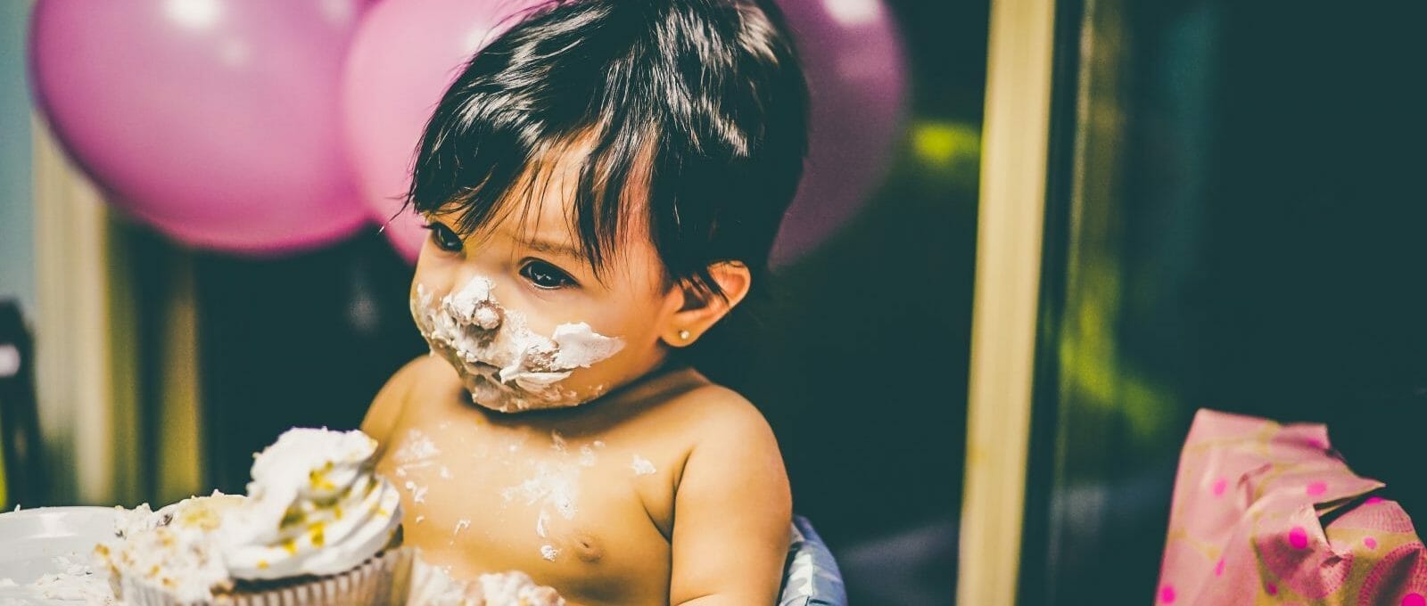 bebê com o rosto sujo de bolo