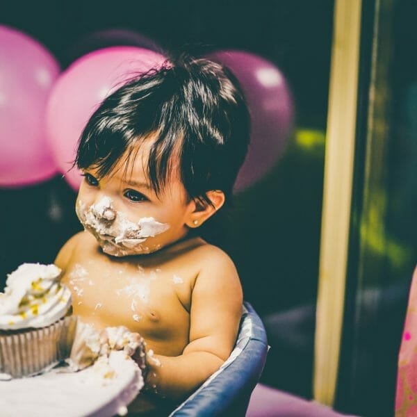 bebê com o rosto sujo de bolo