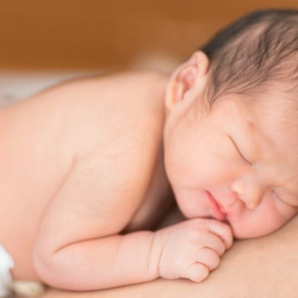 bebê de fraldas dormindo com expressão tranquila no rosto