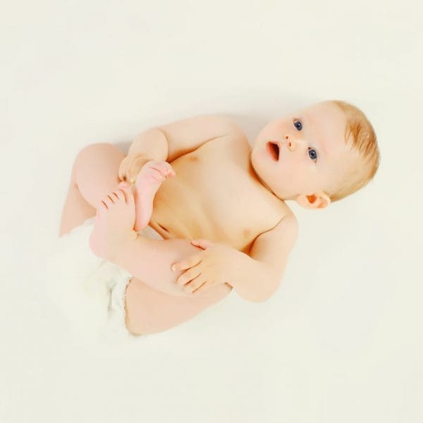 bebê deitado em um chão branco vestindo fralda de algodão