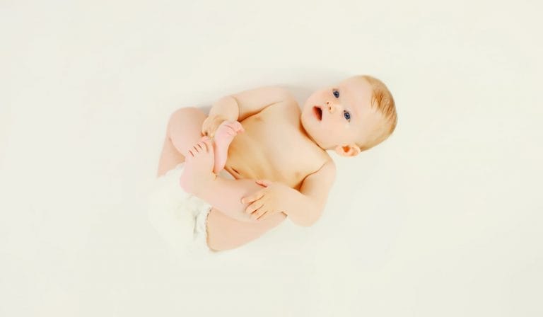 bebê deitado em um chão branco vestindo fralda de algodão