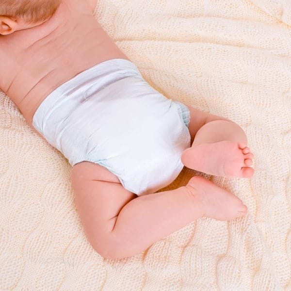bebê deitado na cama de bruços usando fraldas brancas