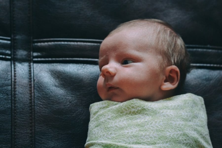 bebê deitado enrolado em uma mantinha em formato de charutinho no bebê