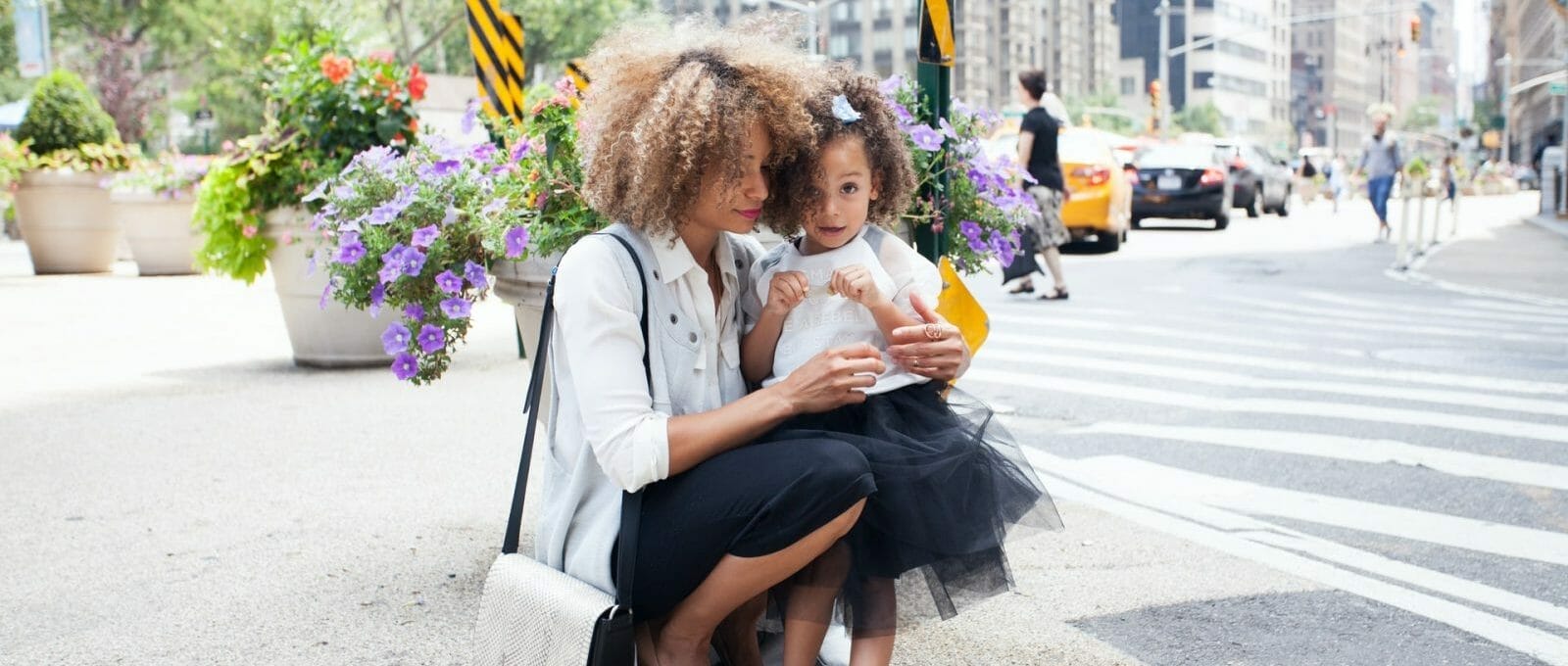 mãe abraçando sua filha no meio da rua, ilustrando o conceito de como criar bem sua filha