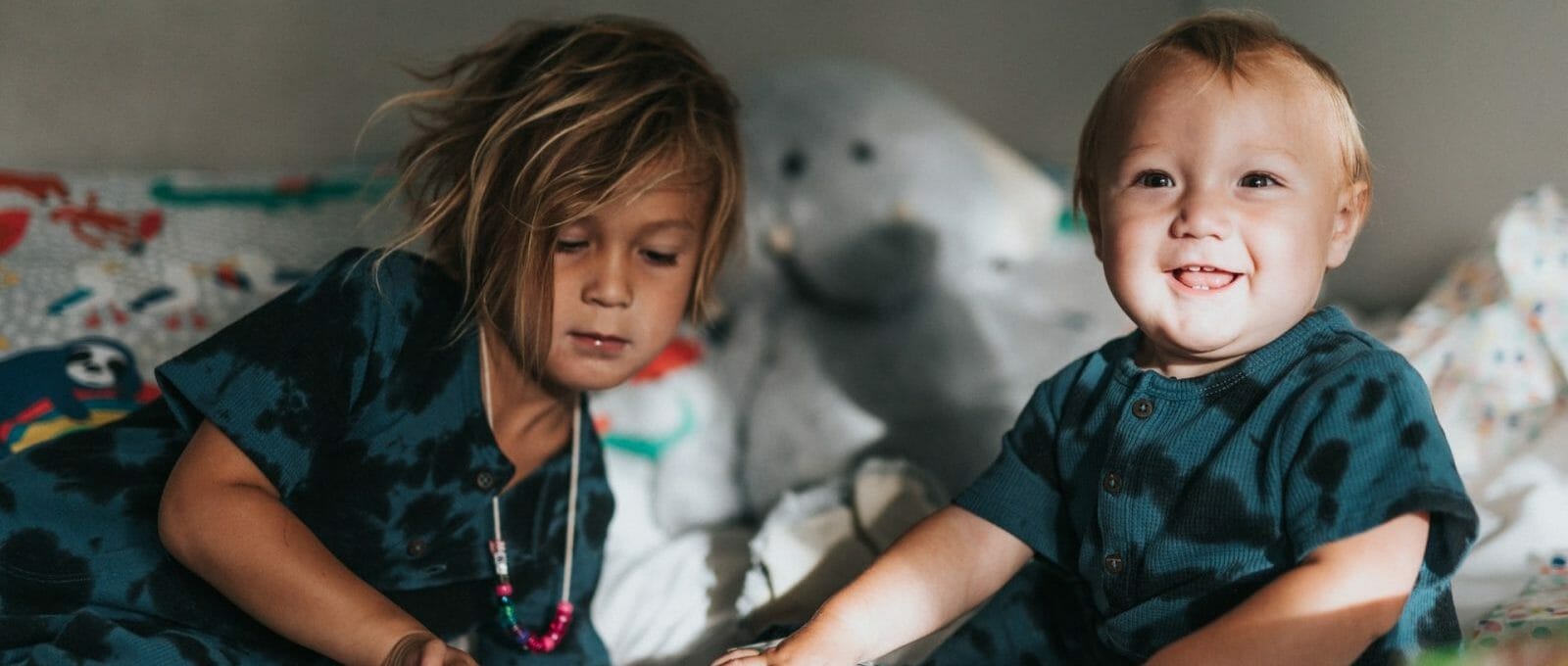 menina brincando com bebê na cama, mostrando como dar atenção ao filho mais velho e evitar o ciúme