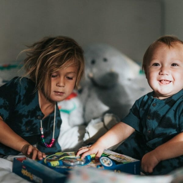 menina brincando com bebê na cama, mostrando como dar atenção ao filho mais velho e evitar o ciúme
