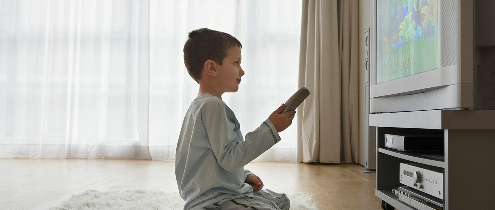 Criança ajoelhada assistindo TV