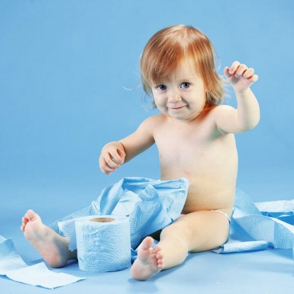 criança sentada em um cenário azul, brincando com rolos de papeis higiênicos azuis durante o desfralde