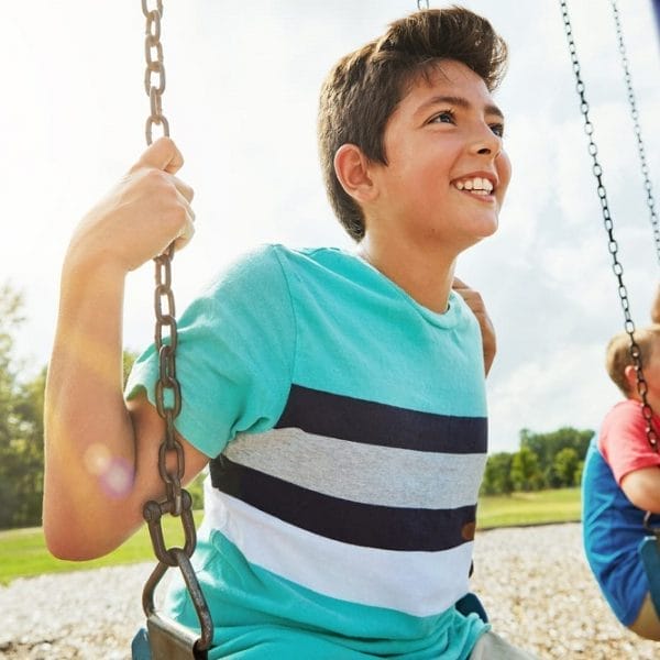 Menino de camisa verde brincando no balanço