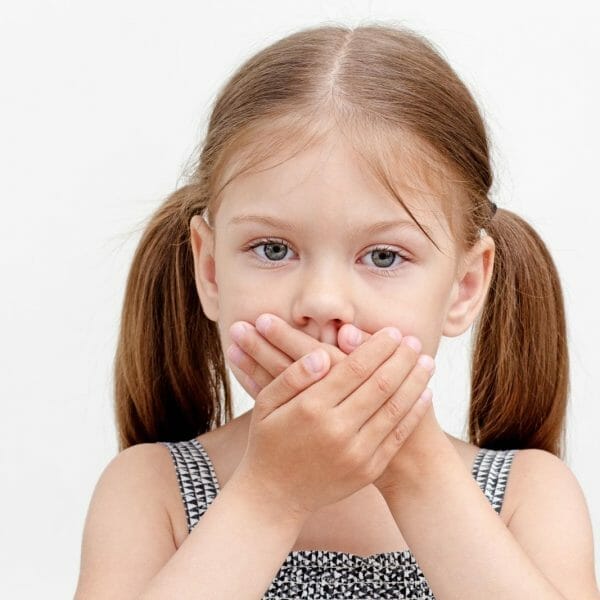 Criança com as mãos na boca, representando o conceito de "meu filho acordou vomitando"