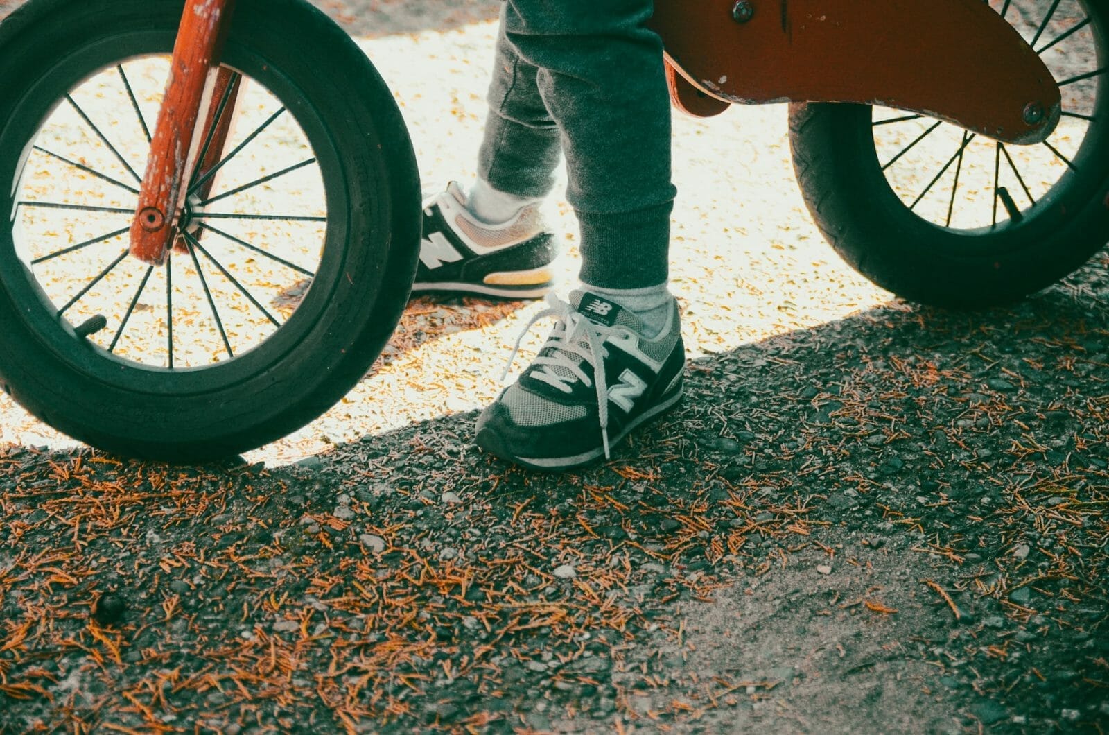 a foto mostra uma criança em uma bicicleta de equilíbrio, com os pés encostados no chão, o que significa que a bike tem o tamanho certo para ela