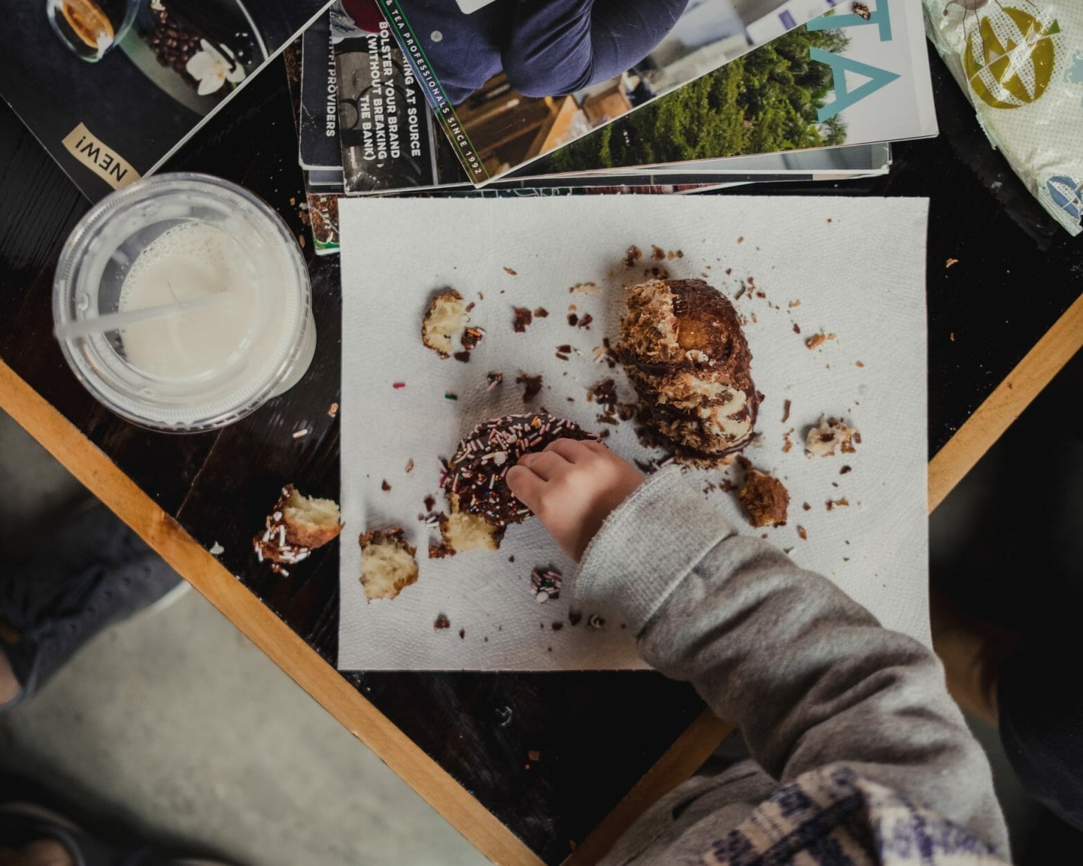 imagem de uma mesa com criança comendo donuts e tomando um milkshake