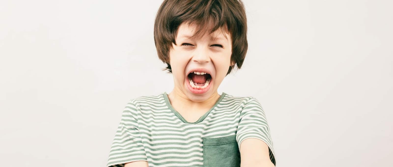 Menino gritando com o punho levantado, ilustrando o conceito de "meu filho não sabe perder"