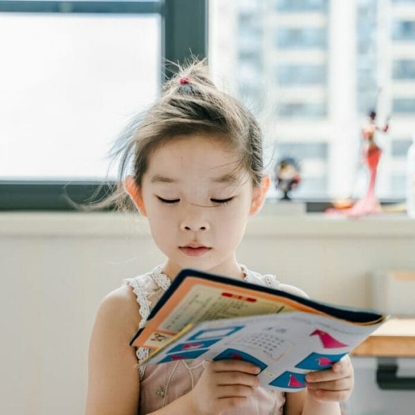Criança lendo livro colorido
