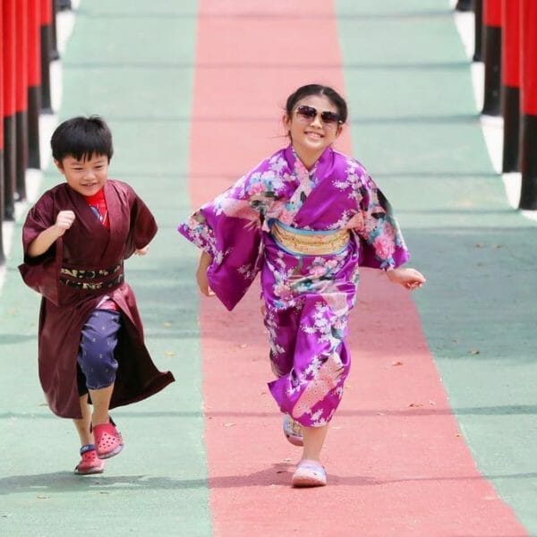menino de quimono preto e menina de quimono rosa correndo em direção à câmera enquanto riem