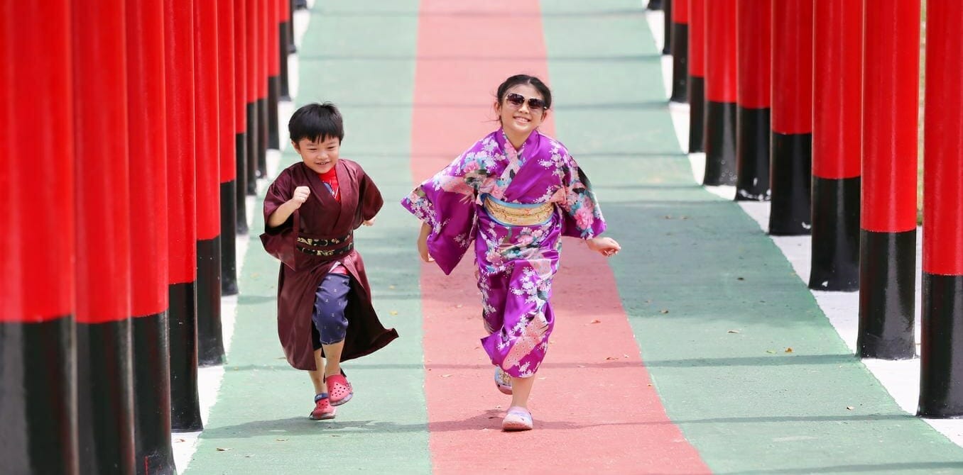menino de quimono preto e menina de quimono rosa correndo em direção à câmera enquanto riem