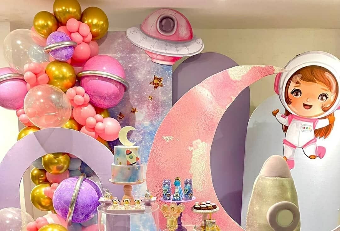 painel de festa de aniversário de astronauta, com balões rosas, desenho de astronauta e lua