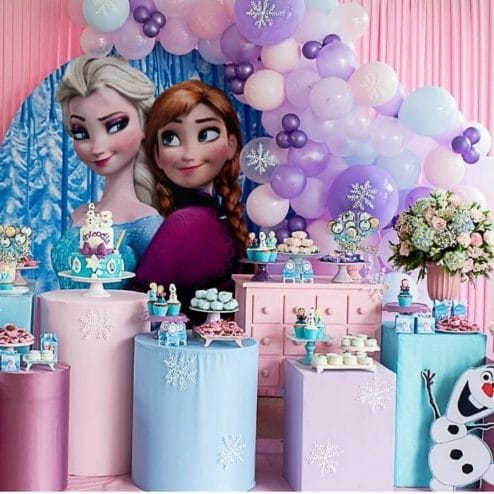 painel de festa infantil da frozen, com as princesas elsa e anna em destaque, e estruturas e balões nas cores rosa, lilás e azul