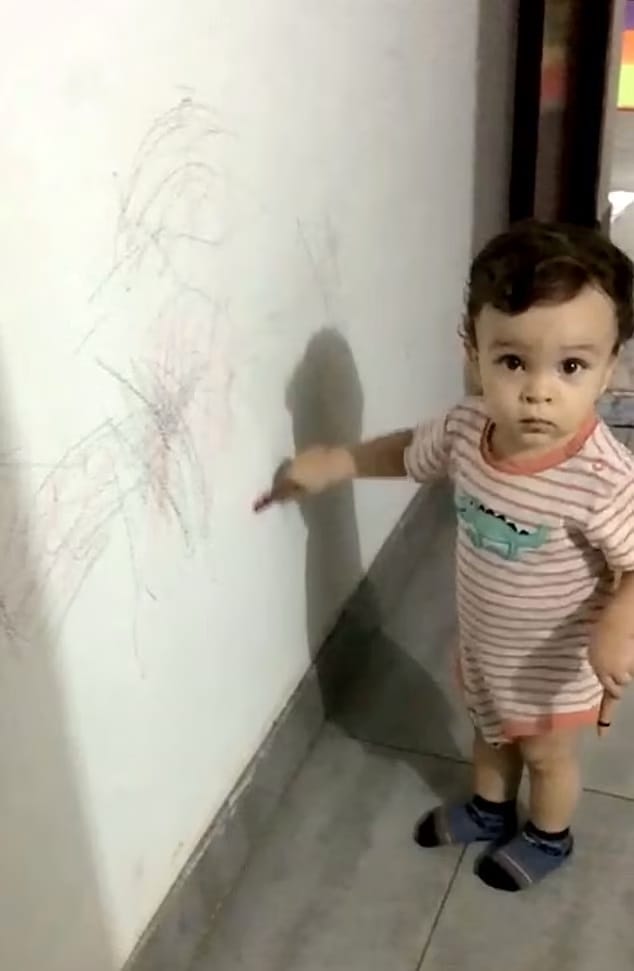 menino desenhando na parede de casa