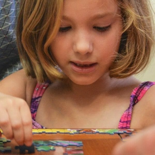 Garota brincando de quebra-cabeça com a família