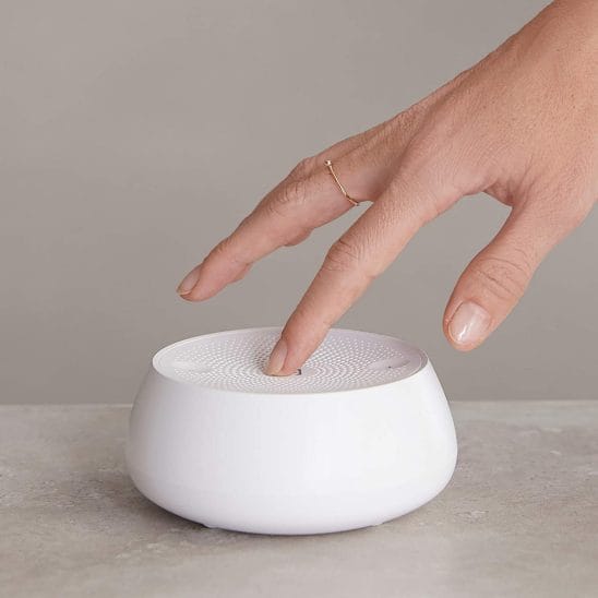mão pressionando o botão de ligar de um aparelho de ruído branco