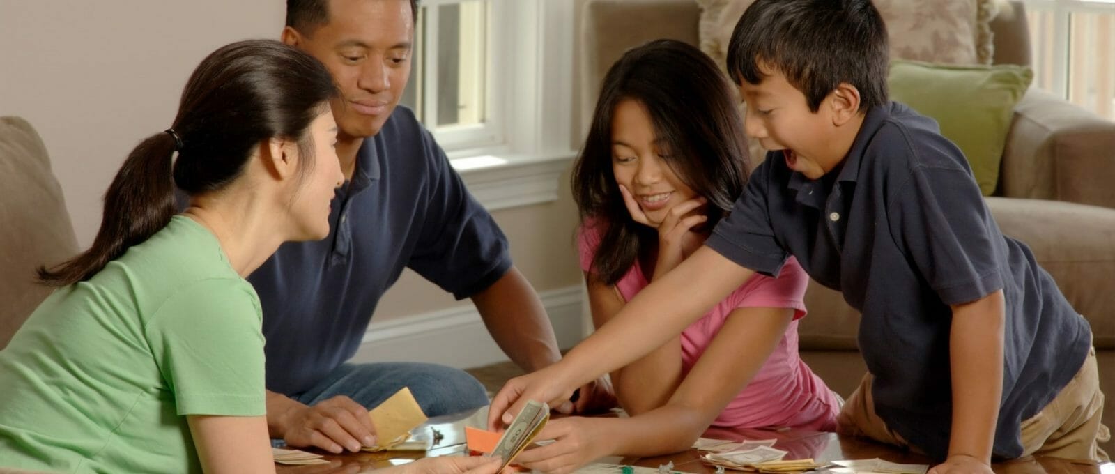 pai, mãe e duas crianças jogando banco imobiliário