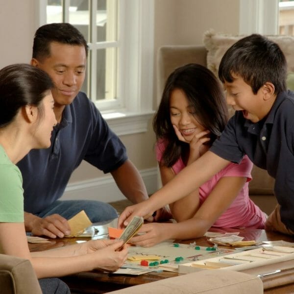 pai, mãe e duas crianças jogando banco imobiliário