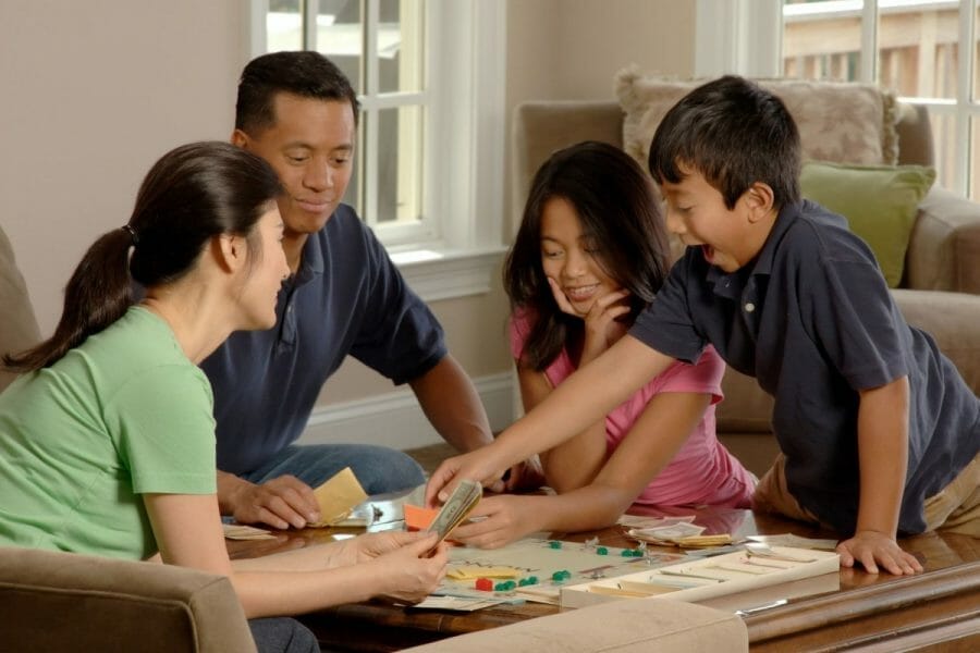 pai, mãe e duas crianças jogando banco imobiliário