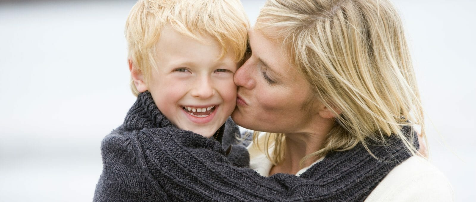 Mãe beijando o filho no rosto na praia