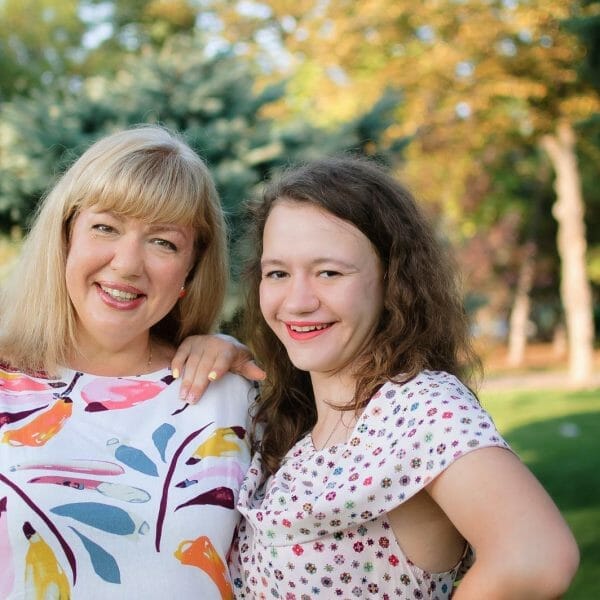 Mãe e adolescente abraçadas e sorrindo no parque, representando o conceito de filha que gosta dos pais