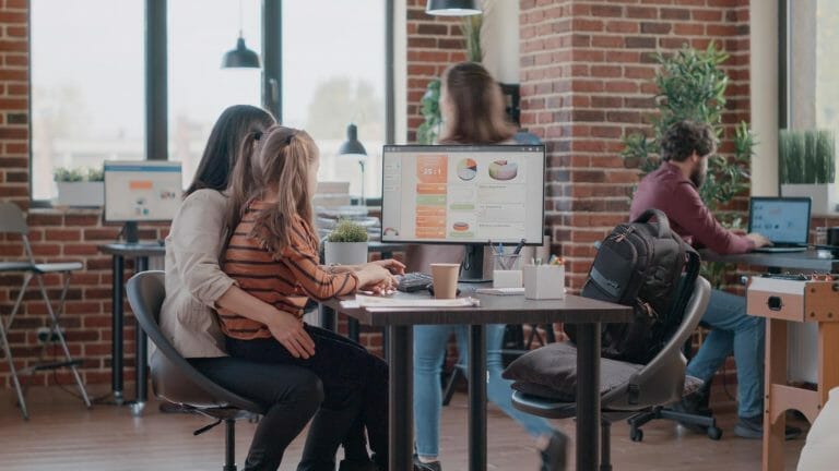 Mãe trabalhando em um computador no escritório com uma criança no colo