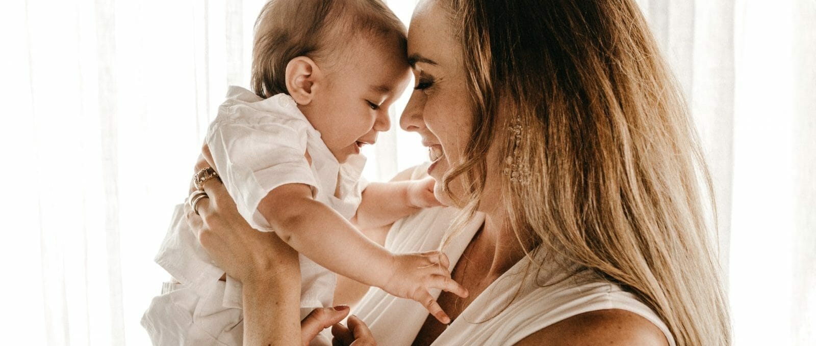 mãe sorrindo e segurando filho bebê no colo