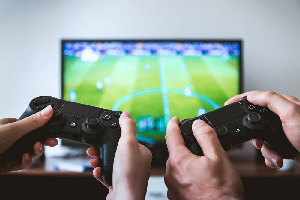 Mãos segurando controles e jogando game de futebol