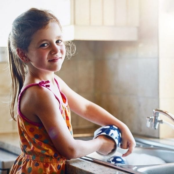 menina lavando louça para ajudar em casa com tarefas domésticas