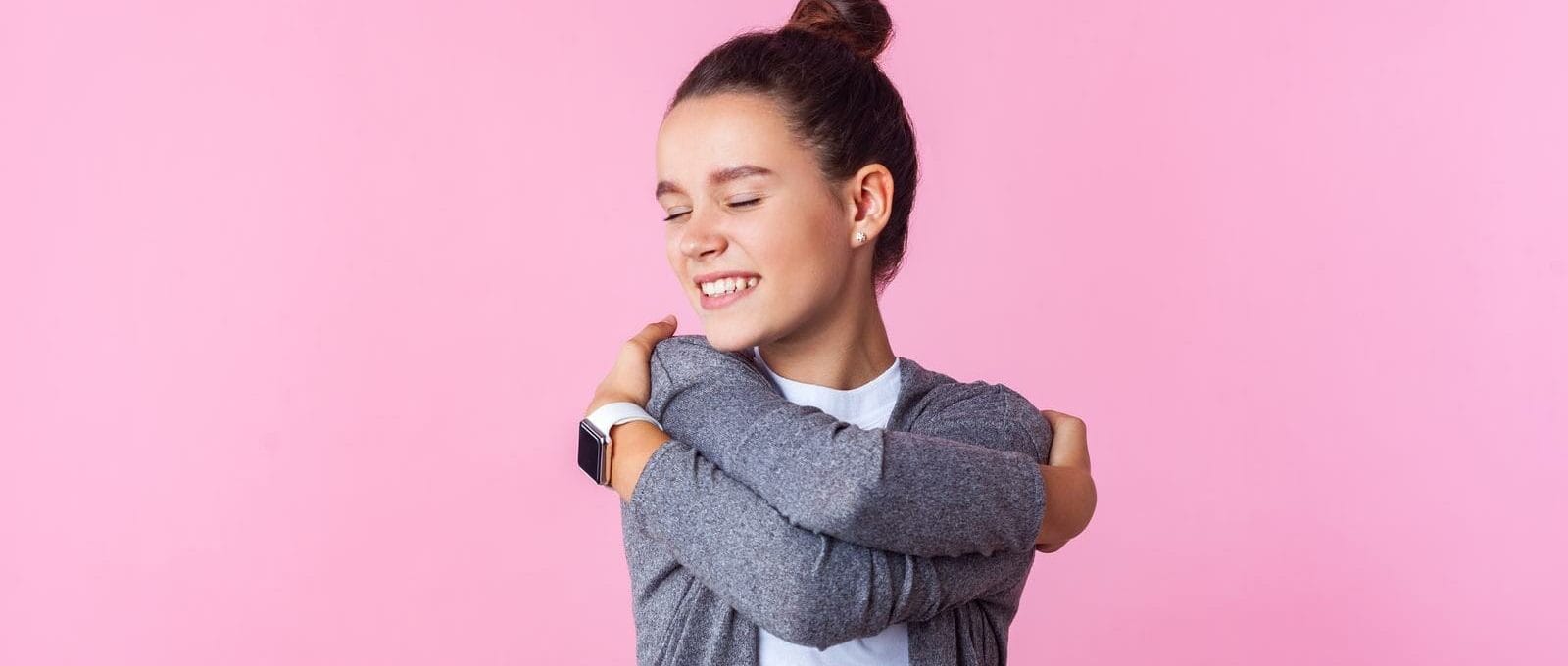 menina feliz e se abraçando, representando o conceito de criar um filho com autoestima,