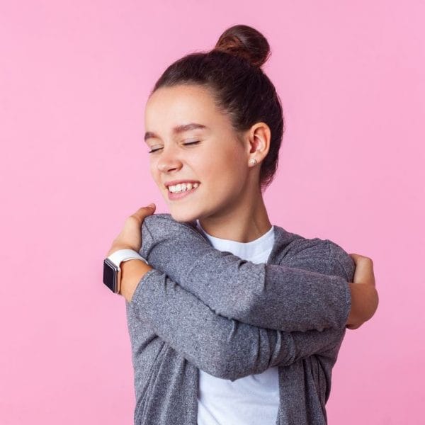 menina feliz e se abraçando, representando o conceito de criar um filho com autoestima,