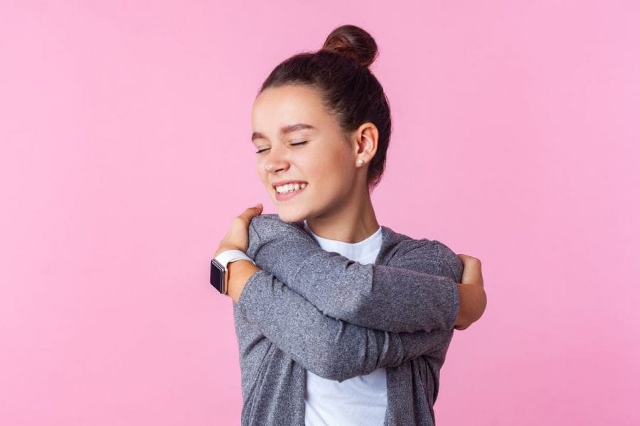 menina feliz e se abraçando, representando o conceito de criar um filho com autoestima,